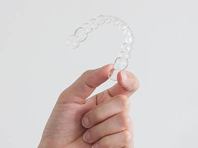 Person holding an Invisalign tray in their hand