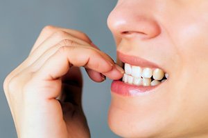 A closeup of a woman biting her nails