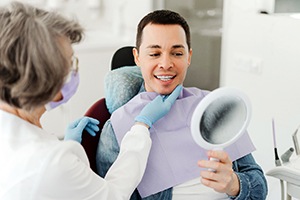 Man smiling at reflection in mirror with dentist