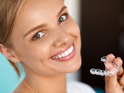 Girl with flawless smile holding Invisalign tray