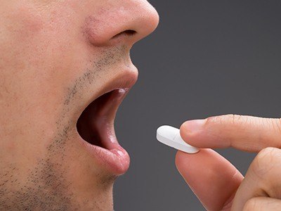 Close up of dental patient taking oral sedative pill