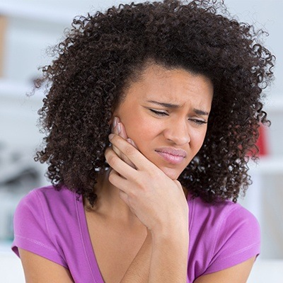 Woman holding her cheek in pain needing wisdom tooth extractions